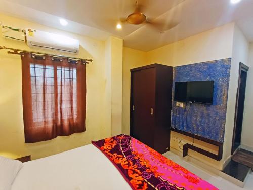 a bedroom with a bed and a flat screen tv at MG Residency in Chikmagalūr
