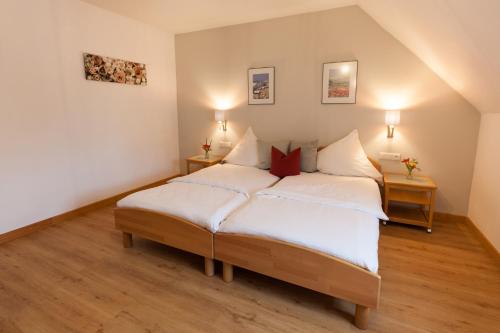 a bedroom with a bed with white sheets and red pillows at Gasthaus Landbrecht in Freising