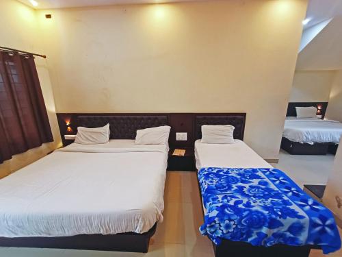 two beds in a room with white sheets at MG Residency in Chikmagalūr