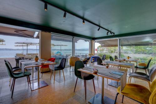 a restaurant with wooden tables and chairs and windows at Hotel Flaminia in Sirmione