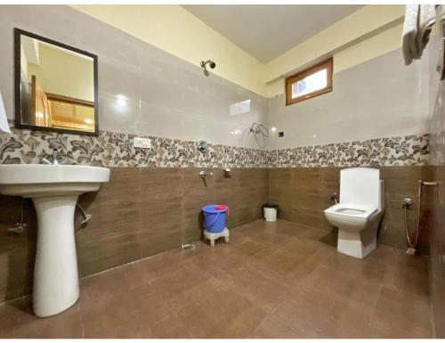 W łazience znajduje się umywalka, toaleta i lustro. w obiekcie Hotel Him Paradise, Manali w mieście Manāli
