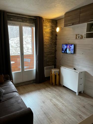 - un salon avec un canapé et une télévision murale dans l'établissement Studio la Foux, à Allos