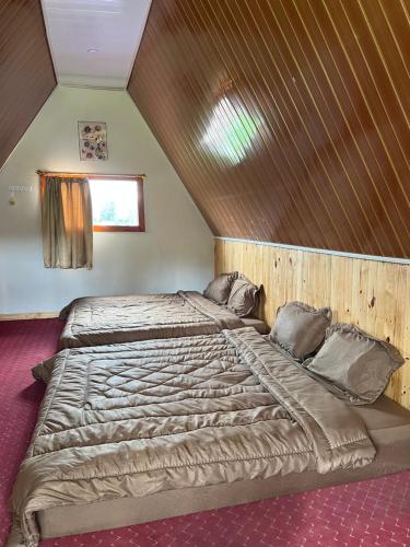 a bedroom with a large bed with a wooden ceiling at Ulina Villa Segitiga Berastagi in Berastagi
