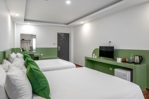 2 camas en una habitación con verde y blanco en The Ram Hotel, en Min Buri