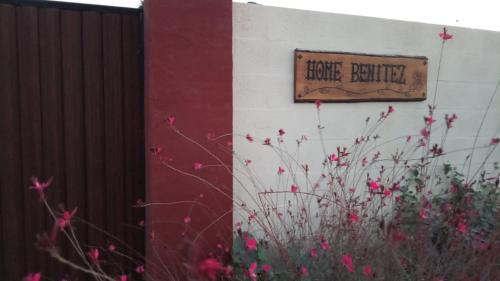 een bord aan de zijkant van een gebouw met roze bloemen bij Home Benitez Pizarra in Pizarra