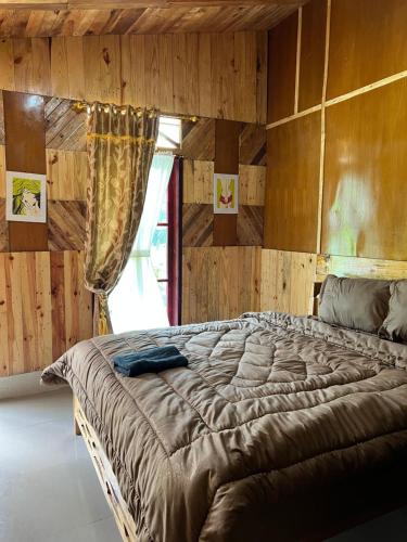 ein großes Bett in einem Zimmer mit Holzwänden in der Unterkunft Ulina Homestay VIP Berastagi in Berastagi