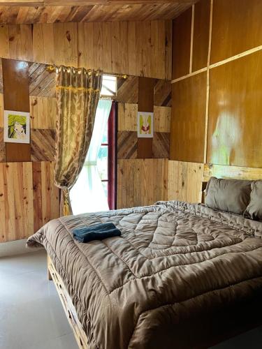 ブラスタギにあるUlina Homestay VIP Berastagiの木の壁の部屋にある大きなベッド