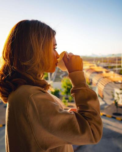 a woman drinking a drink from a cup at Damask Resort in Jabal Al Akhdar