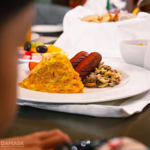 a plate of food with hot dogs and a omelet at Damask Resort in Jabal Al Akhdar