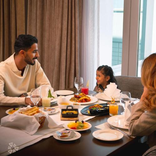 a family sitting at a table eating food at Damask Resort in Jabal Al Akhdar