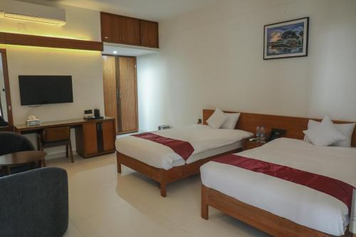 um quarto de hotel com duas camas e uma televisão em JAKAS Resource Center em Helkunda