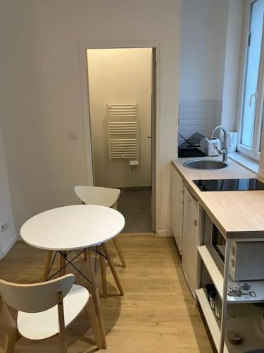une petite cuisine avec une table et des chaises blanches dans l'établissement Leloir Appartment 2, à Tourcoing