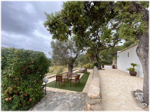 einen Garten mit einem Tisch, Stühlen und Bäumen in der Unterkunft Can Vich in Sant Carles de Peralta