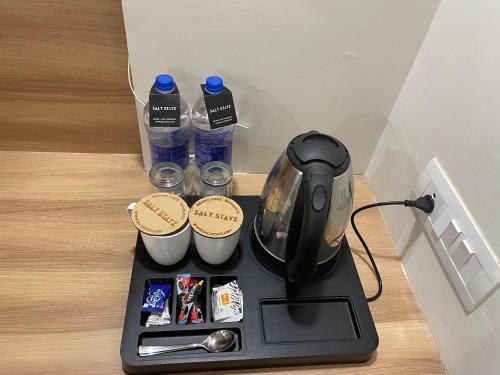 a coffee maker with two bottles of water and cups at Saltstayz Premier - Golf Course Extension Road in Gurgaon