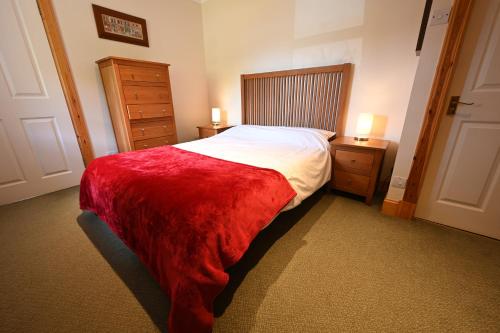 - une chambre avec un grand lit et une couverture rouge dans l'établissement Swallow Cottage, à Fort William