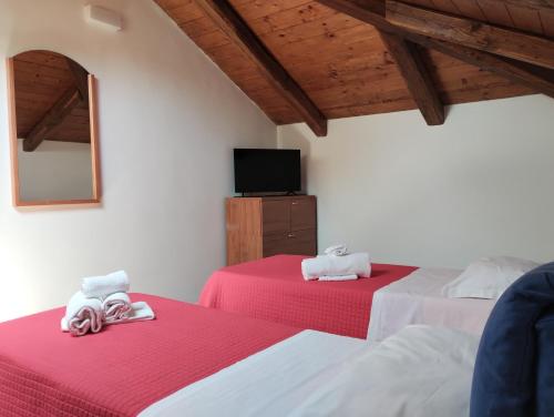 - une chambre avec 2 lits dotés de draps rouges et une télévision dans l'établissement Guest House La Casa del Mandatario, à LʼAquila