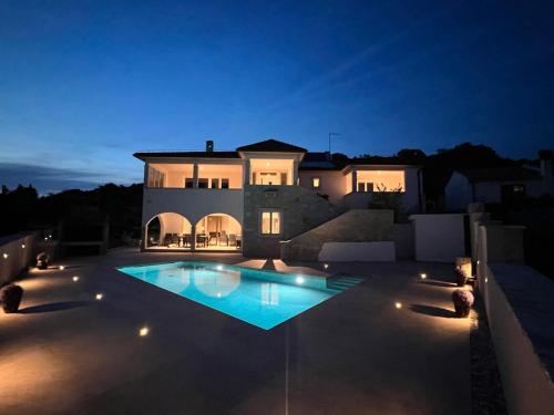 une grande maison avec une piscine la nuit dans l'établissement Villa Salteria 3, pool, private territory, pinery, à Rovinj