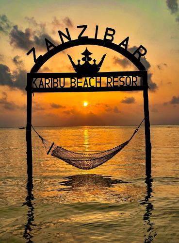 a hammock in the ocean with a sunset in the background at Karibu Beach Resort - Adults Only in Pongwe