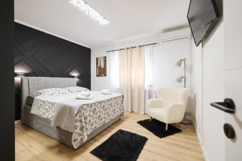 een slaapkamer met een bed en een stoel bij Oscar & Leo Apartments in Zadar