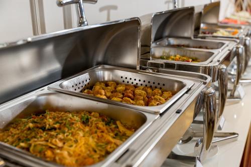 a row of trays of food in a kitchen at Prime New Hotel in Nha Trang