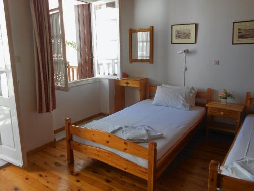 a bedroom with a bed and two windows at Aggela Guesthouse in Skopelos Town