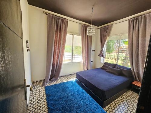 ein Schlafzimmer mit einem blauen Bett und einem Fenster in der Unterkunft Villa de Ferme Wafaa - Location de Rêve avec Piscine près de Mazagan in El Jadida