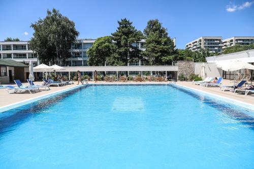 a large swimming pool with chairs and a building at Hotel Dorna in Mamaia