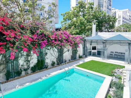 a swimming pool in a yard with pink flowers at Yo-House in Costa da Caparica