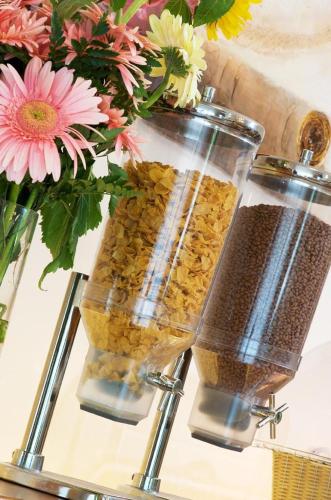 two containers filled with food next to a vase with flowers at Hotel Roma in Ravenna