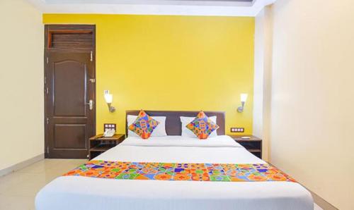 ein Schlafzimmer mit einem großen Bett mit gelber Wand in der Unterkunft FabHotel Span Executive in Pune