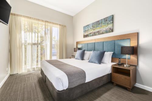 a bedroom with a large bed and a large window at Quest Albury on Townsend in Albury