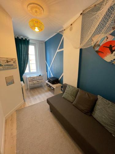 - un salon avec un canapé et un mur bleu dans l'établissement Le Bleu, à Trouville-sur-Mer