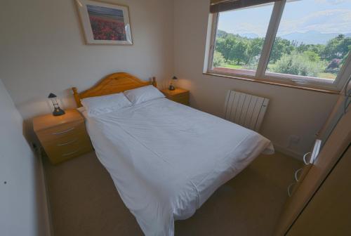 a bedroom with a white bed and a window at Ash, Birch and Rowan Cabins in Onich