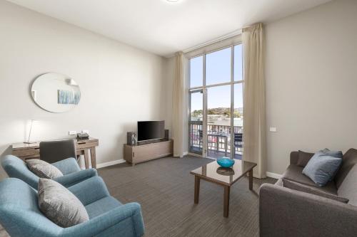 a living room with two blue chairs and a tv at Quest Albury on Townsend in Albury