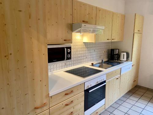 uma cozinha com armários de madeira, um lavatório e um micro-ondas em Venti Maris em Kellenhusen