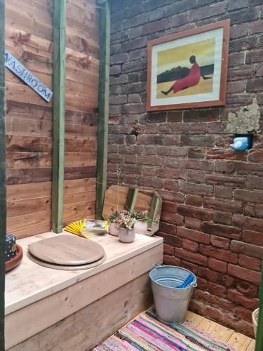 Zimmer mit einem Tisch und einer Ziegelwand in der Unterkunft The Potting Shed in Manuden