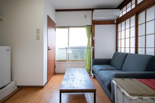 a living room with a blue couch and a table at Rea東向島4丁目 in Tokyo