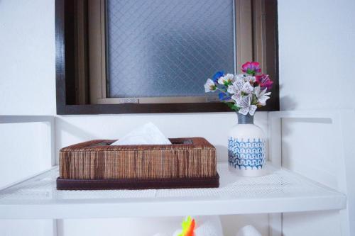 a basket and a vase with flowers on a shelf at HOTEL AARON通天東 in Osaka