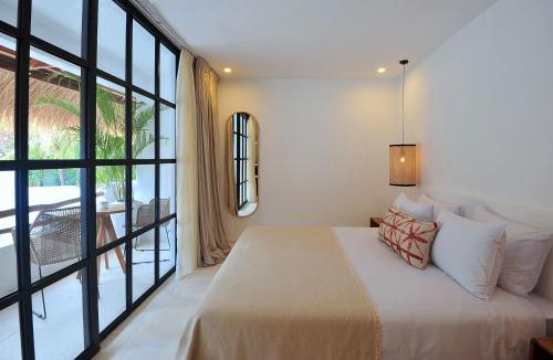 um quarto com uma cama e uma grande janela em Amara Uluwatu em Uluwatu