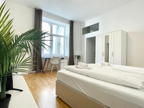 um quarto branco com uma cama grande e uma planta em Cosy Residence at famous Vienna Kutschkermarkt em Viena