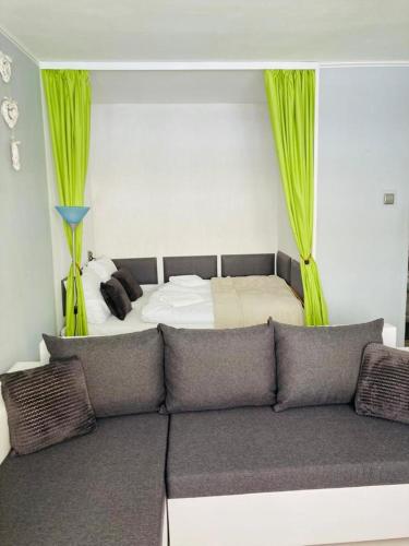 a bedroom with a bed and a couch with green curtains at Apartamenty Every Sky Plac Ratuszowy 30 in Jelenia Góra