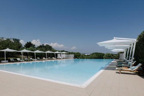 una grande piscina con sedie e ombrelloni di Casale del Murgese Country Resort a Savelletri