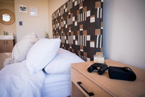 a bedroom with a bed with a wooden side table with a camera at Kamoka Camp in Hoedspruit