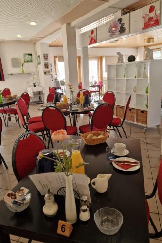 a dining room with tables and red chairs at Spreewaldhotel Seerose in Burg