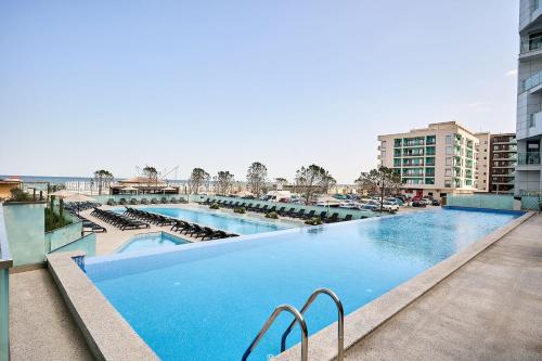 a large swimming pool with chairs and buildings at VDR Holiday Apartment 139 in Infinity Beach Resort - parking in Mamaia