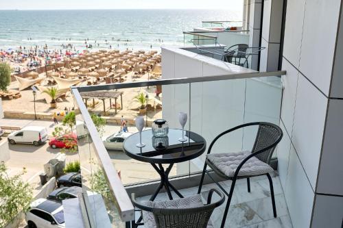 a balcony with a table and chairs and a beach at VDR Holiday Apartment 139 in Infinity Beach Resort - parking in Mamaia