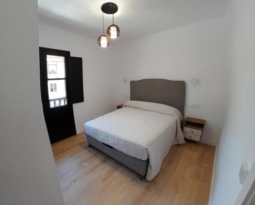 a white bedroom with a bed and a window at Apartamento Corazón de Liébana in Potes