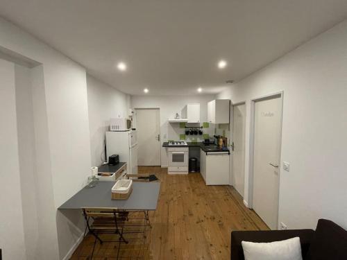 una cocina con electrodomésticos blancos y una mesa en una habitación en Le péageois : Appartement lumineux et calme, en Bourg-de-Péage