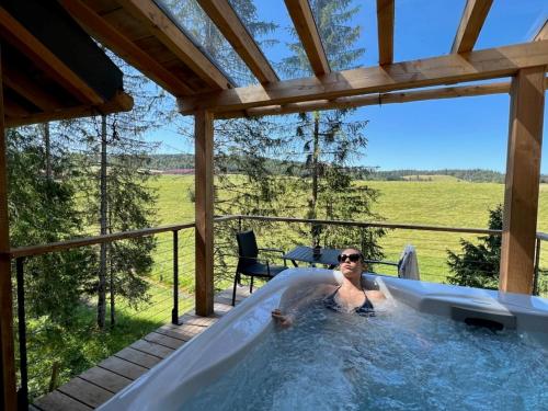 a woman in a hot tub on a patio at Les Écrins du Val de Mouthe, JURA in Petite Chaux