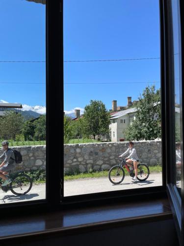 Ein paar Leute, die durch ein Fenster Fahrrad fahren in der Unterkunft Teona's Guesthouse in Mestia in Mestia